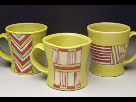 Yellow ceramic mugs with red geometric designs by student Eric Gooch