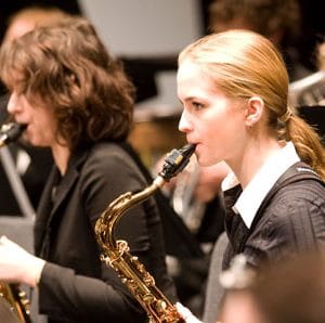 two women playing saxophone amongst other band members