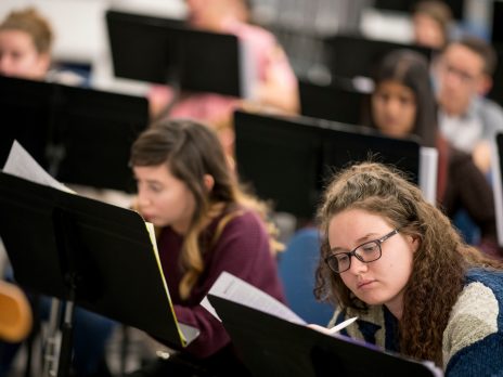 Two female students use music stands to write.