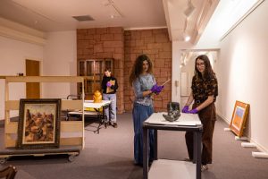 Students work in a museum gallery examining the condition of objects. 