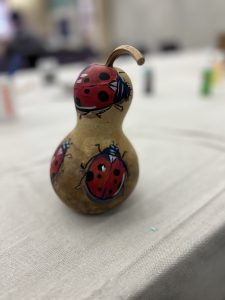 A student painted gourd with images of red and black ladybugs.