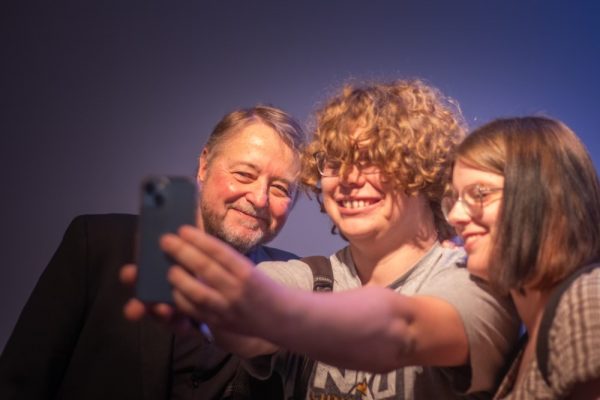 Two students take a selfie with Luis Urrea.
