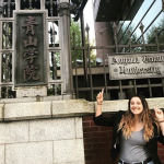 NAU student posing in front of a building with Japanese writing on it.