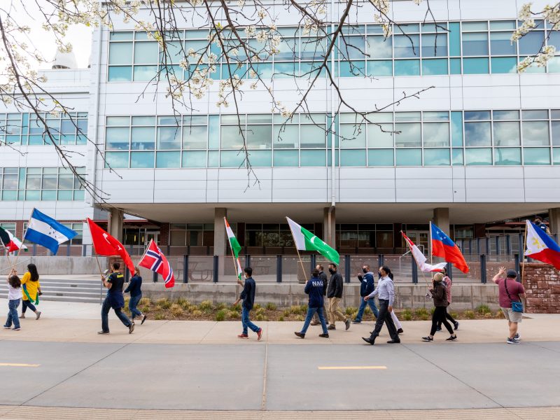 Students walk on campus folding flags in the parade of nations.