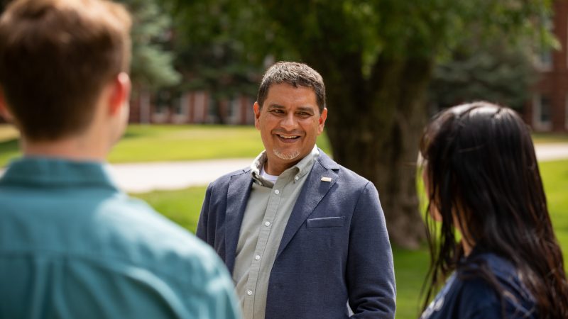 Dr. Jose Luis Cruz Rivera talks with students under a big tree on the NAU Flagstaff campus.