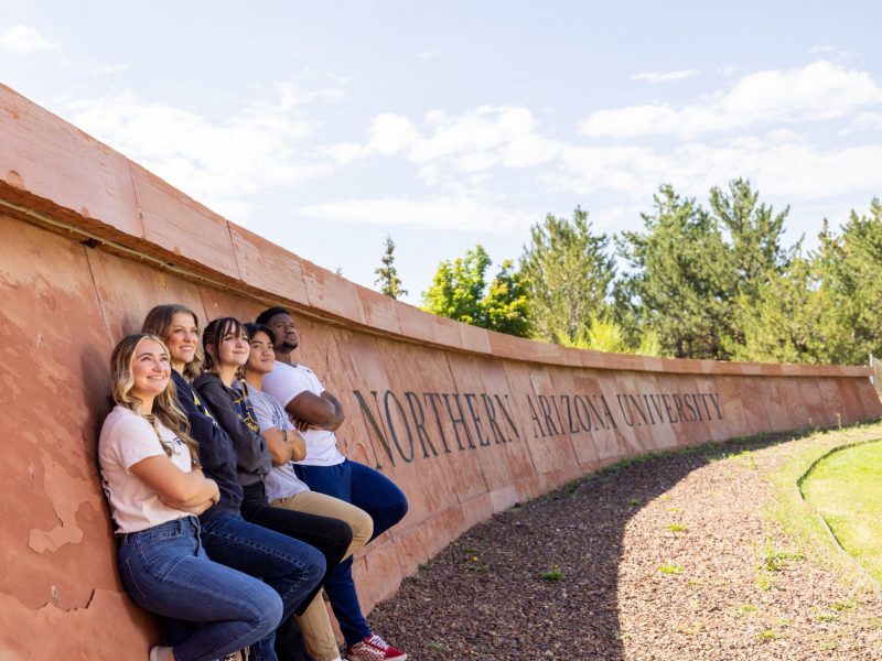 Students stand in front of the N A U sign at Flagstaff campus.