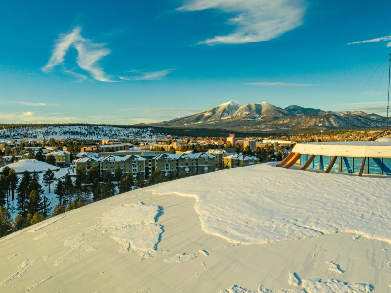 Aerial photo of N A U Flagstaff campus with snow-covered mountains in the background.