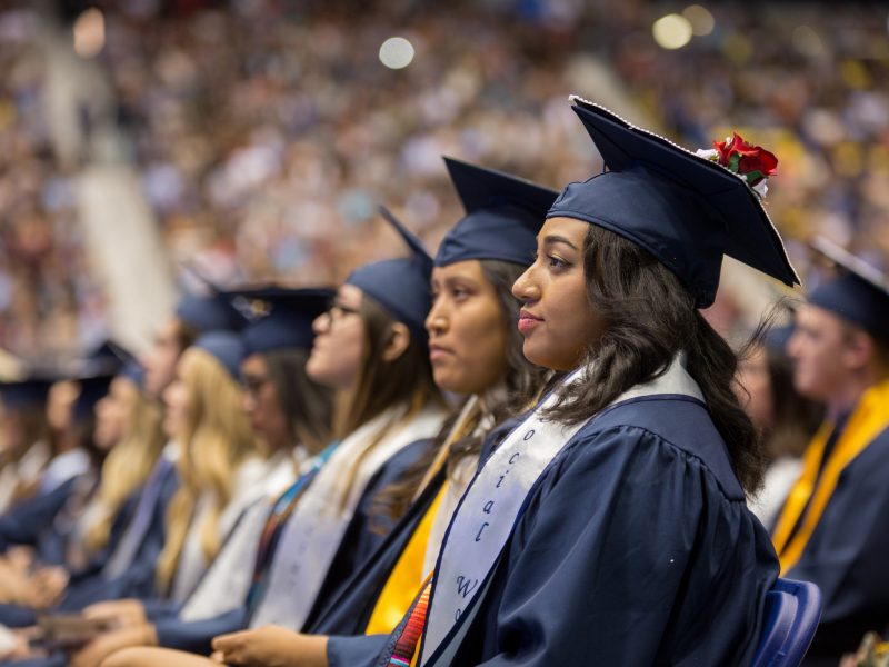 A row of students wearing caps and gowns at a Commencement ceremony.