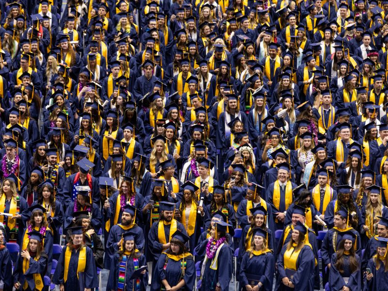 Thousands of Northern Arizona University graduates sitting in a stadium at Spring Commencement in Flagstaff, Arizona.