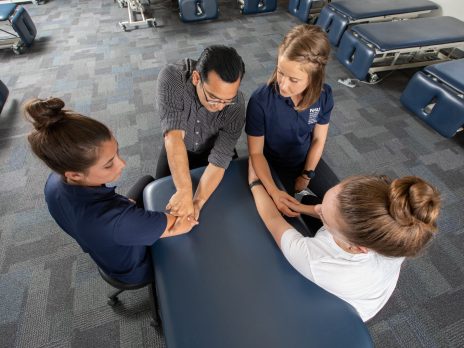 A female student copies a physical therapy technique on a student serving as a patient.