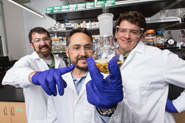 Men in lab coats holding a vile up to the camera