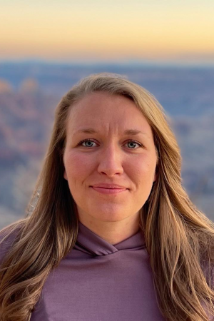 A photo of Dixie Clinkenbeard who has long sandy blonde hair, and is against a background of the Grand Canyon.