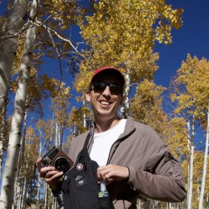 Skyler Bordeaux who is wearing sunglasses and posting with yellow aspens