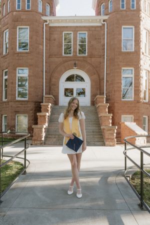 Claire Wahlberg with her graduate cap outside of Old Main in Flagstaff AZ