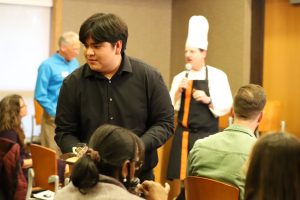 An NAU students delivers food while Chef Mark Molinaro, NAU, presents at the October 27 ABRC workshop.