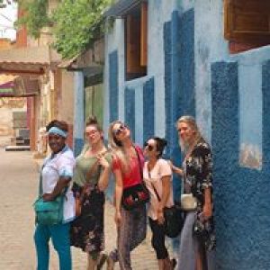Five women posing in front of a blue wall.