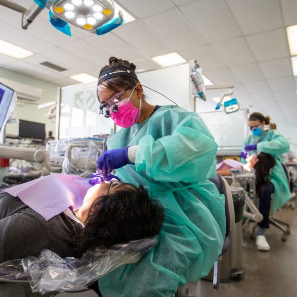 A dental hygienist cleaning a person's teeth.