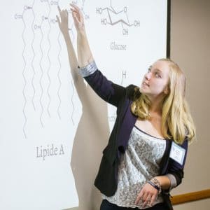 An NAU student pointing to her example on a board