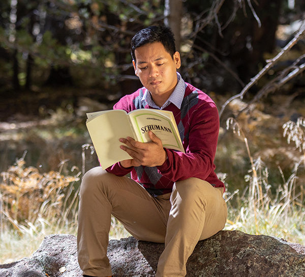 Ye Lynn Han sits on a rock outdoors, reading