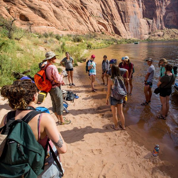 Students and an instructor stand on the edge of a body of water at the Colorado Plateau