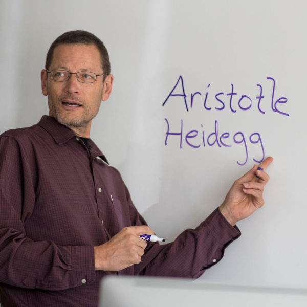 George Rudebusch writes the names of philosophers on a whiteboard