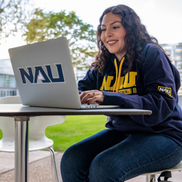 Valeria Sandoval working outside on a laptop at the NAU–Yuma campus.