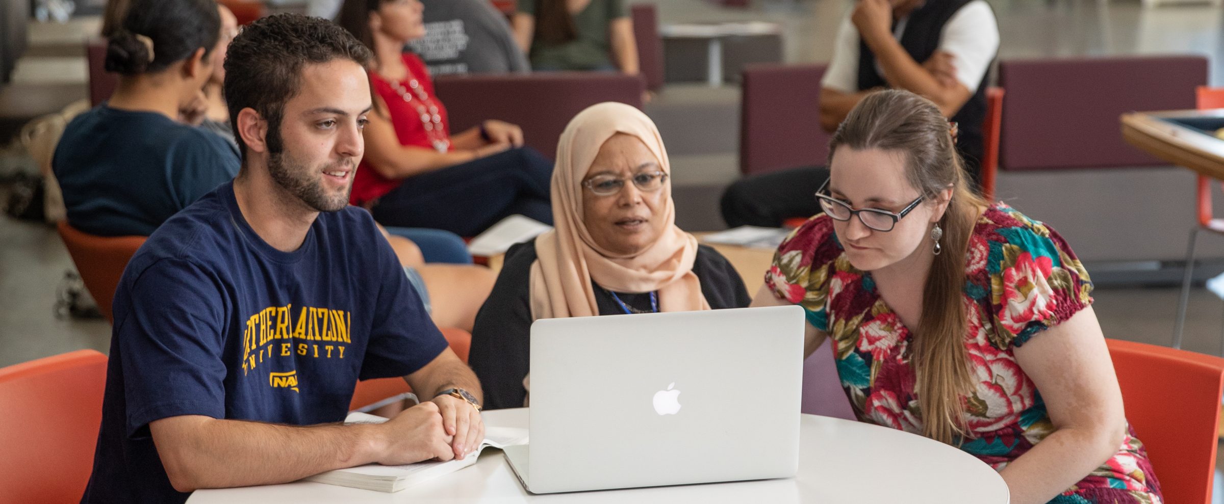 Three NAU students gathered around a laptop.