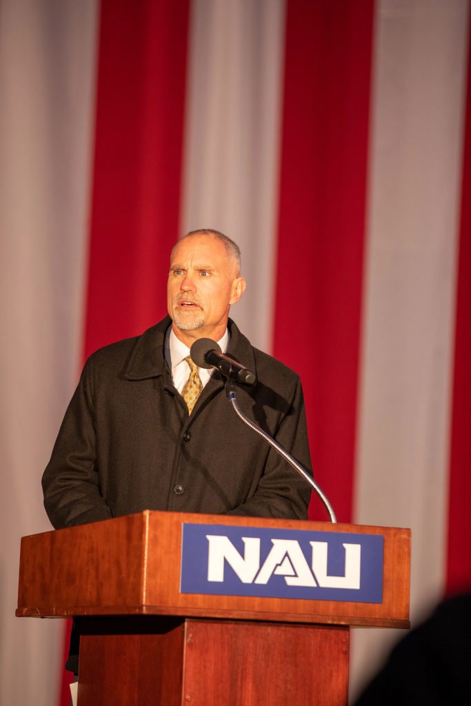 Pete Yanka speaking behind an NAU lectern, in front of a red and white background.
