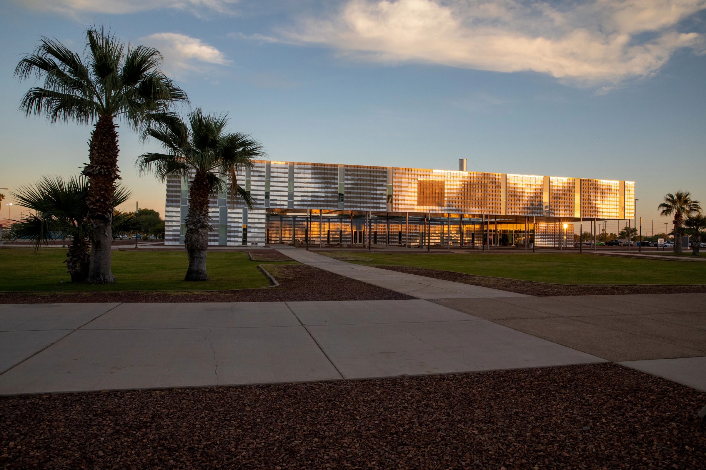 Building on NAU–Yuma campus at dusk with light reflecting off building. Palm trees are on both sides of the building.