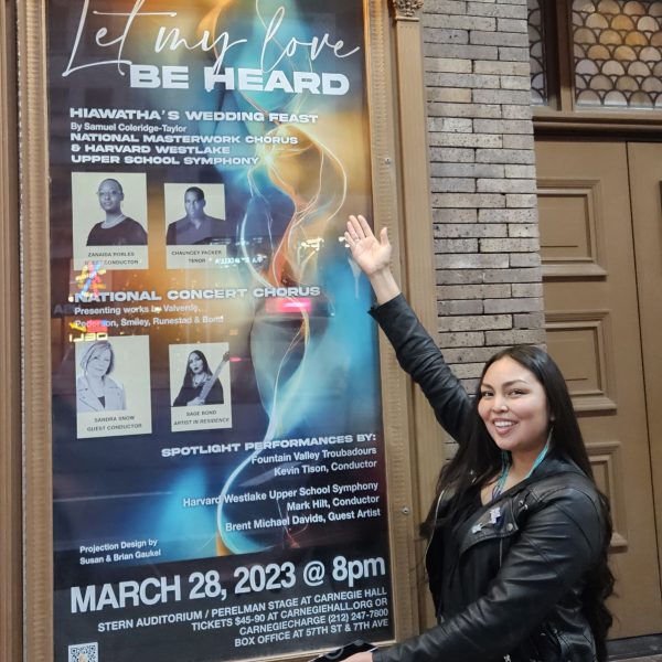 NAU Music student Sage Bond points to poster outside of the concert series highlighting her performance at Carnegie Hall.
