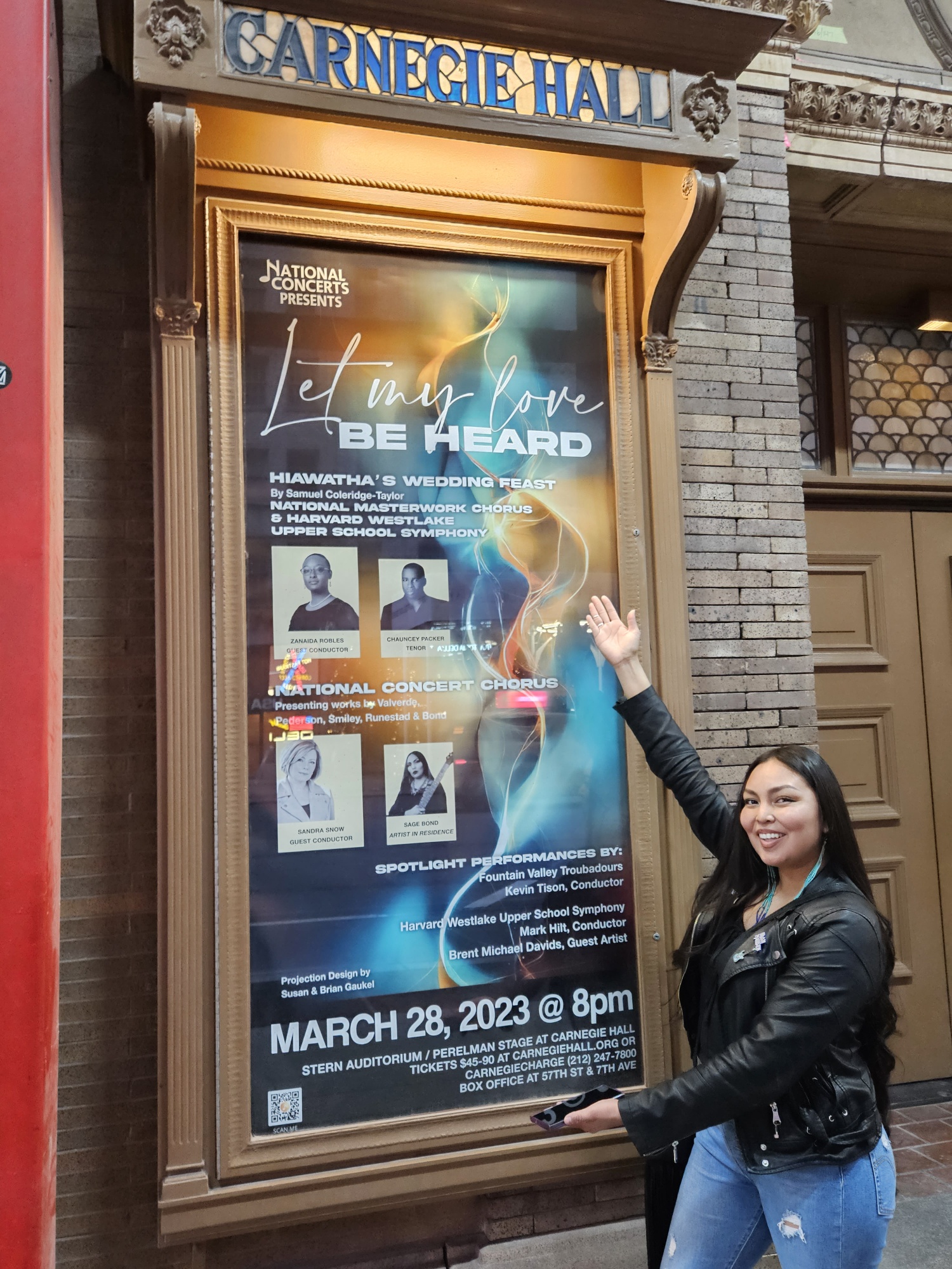 NAU Music student Sage Bond points to poster outside of the concert series highlighting her performance at Carnegie Hall.