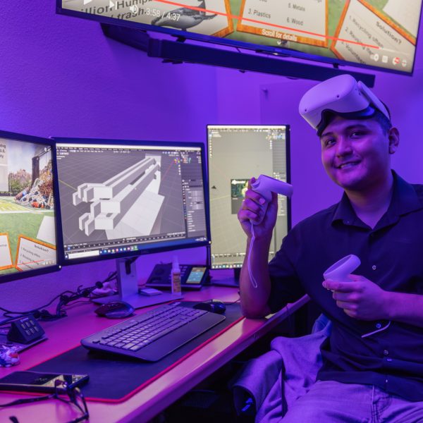 N A U senior Visual Communication student, Dadric Riggs, smiles while showcasing the virtual reality equipment used for their research on waste issues in the United States.