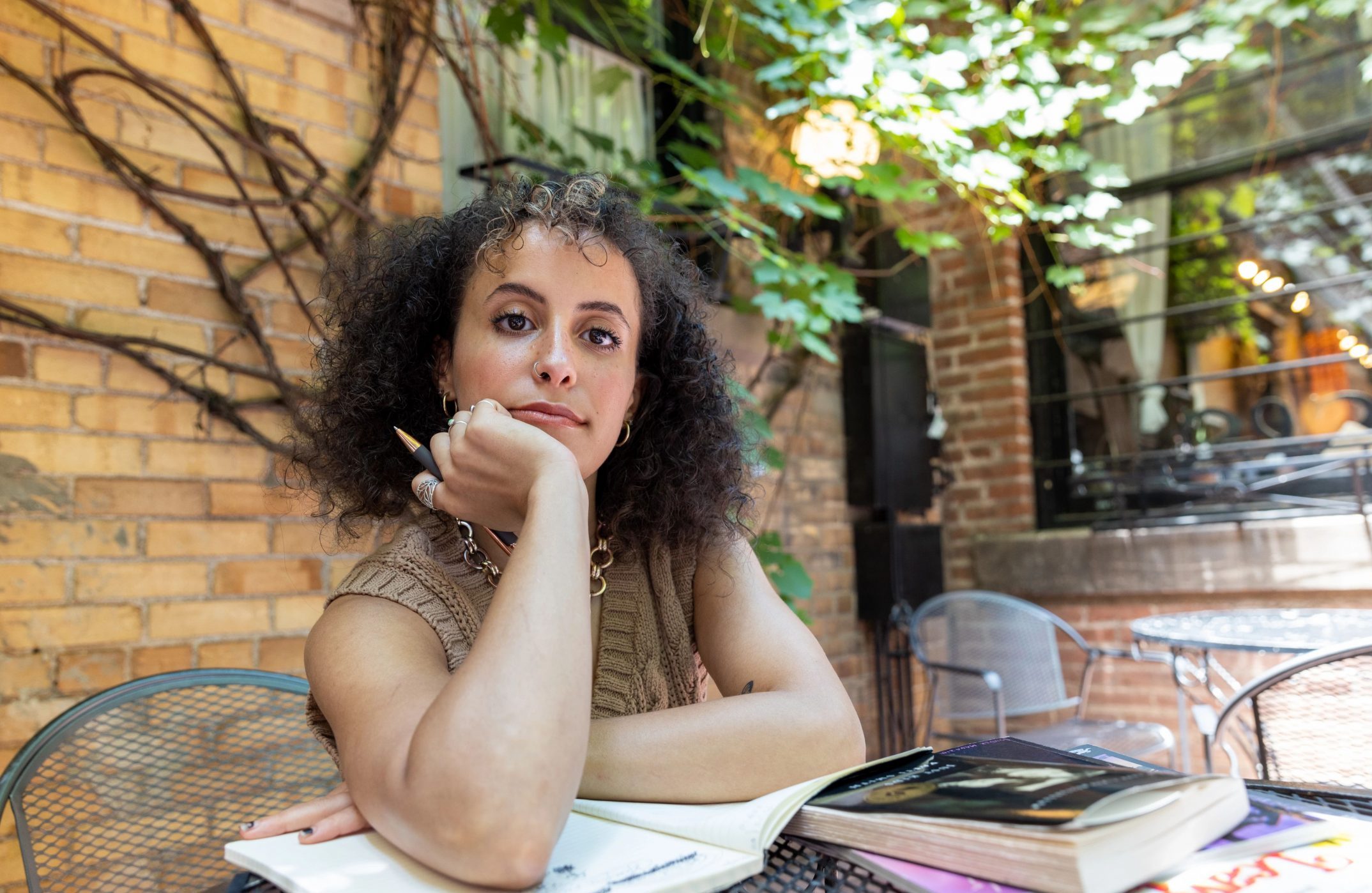 NAU alumna Micaela Merryman writes at courtyard table under a tree.