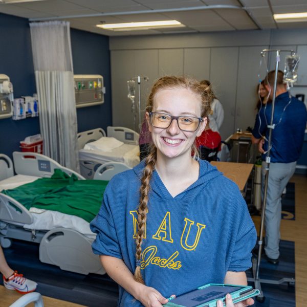 Sara Thomasson, student in NAU’s hybrid Doctor of Physical Therapy program, smiles at camera as other students work in the background.