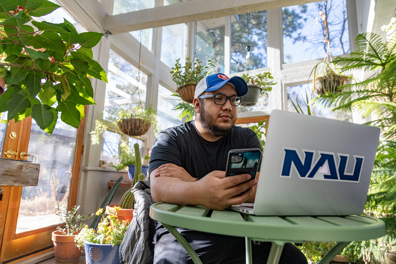 A student sitting in a bright room with a lot of plants.