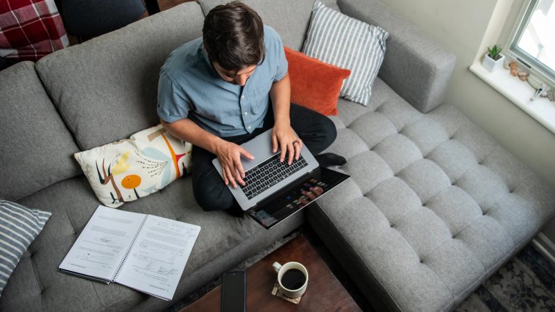 A students working on his laptop on his couch.