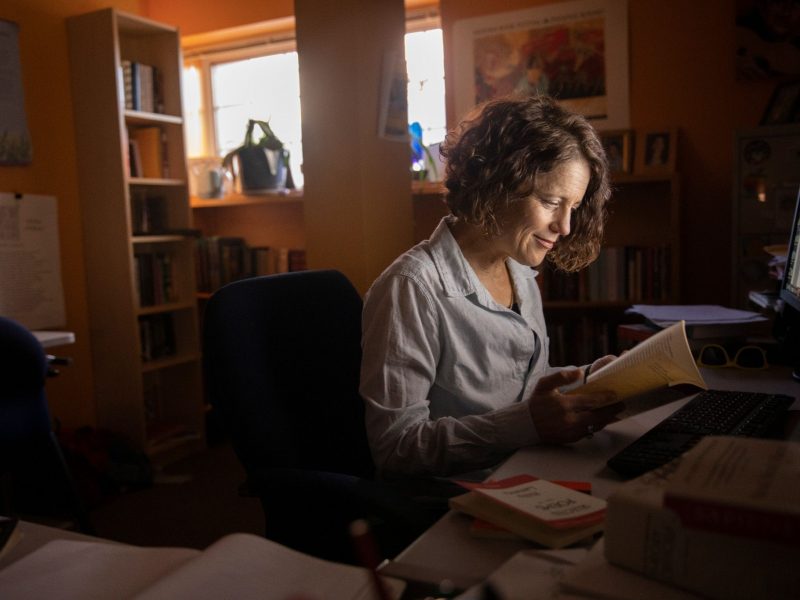 A professor reading a book at her desk.