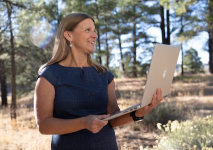 Julie Mueller working on a computer in the forest.