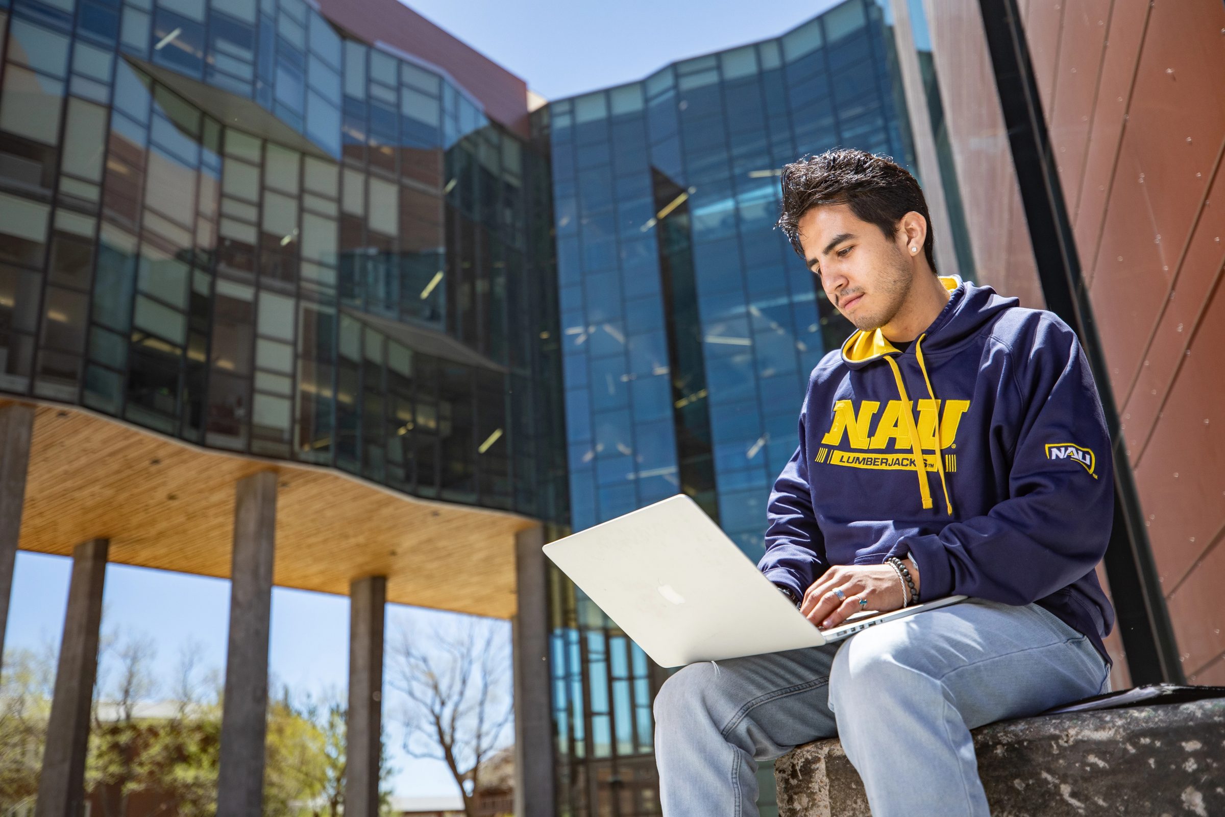 Student reads on laptop while sitting outside