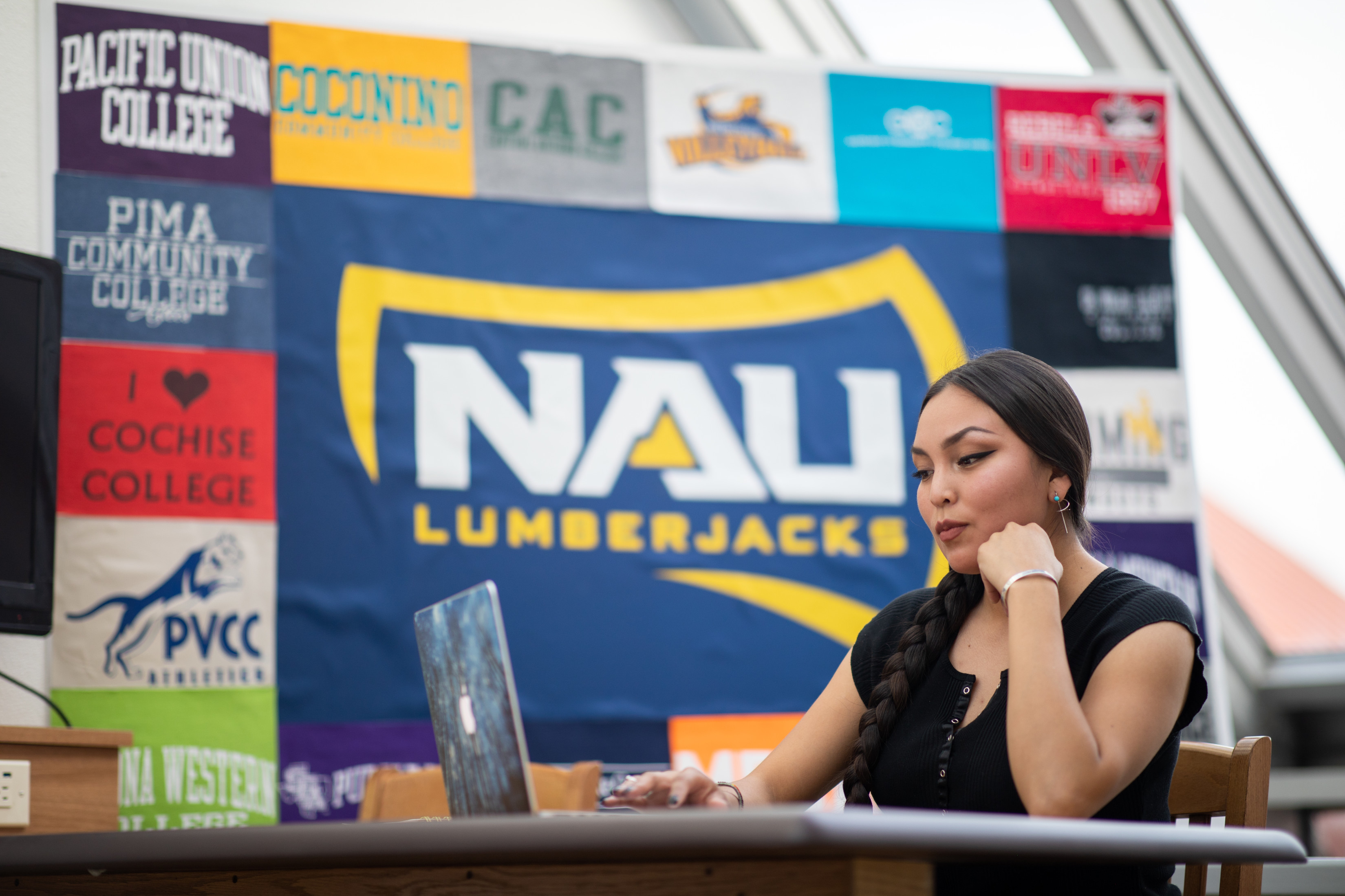 NAU student works on a laptop in front of a banner.