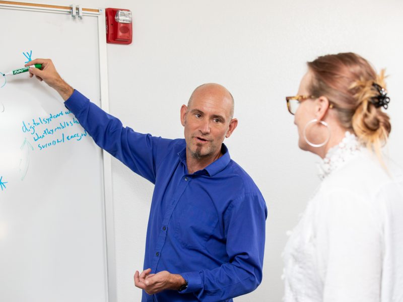 University Marketing staff writes on a whiteboard during a meeting