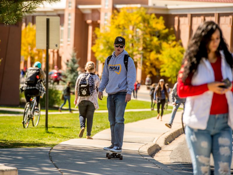 NAU student rides a skateboard on Flagstaff campus