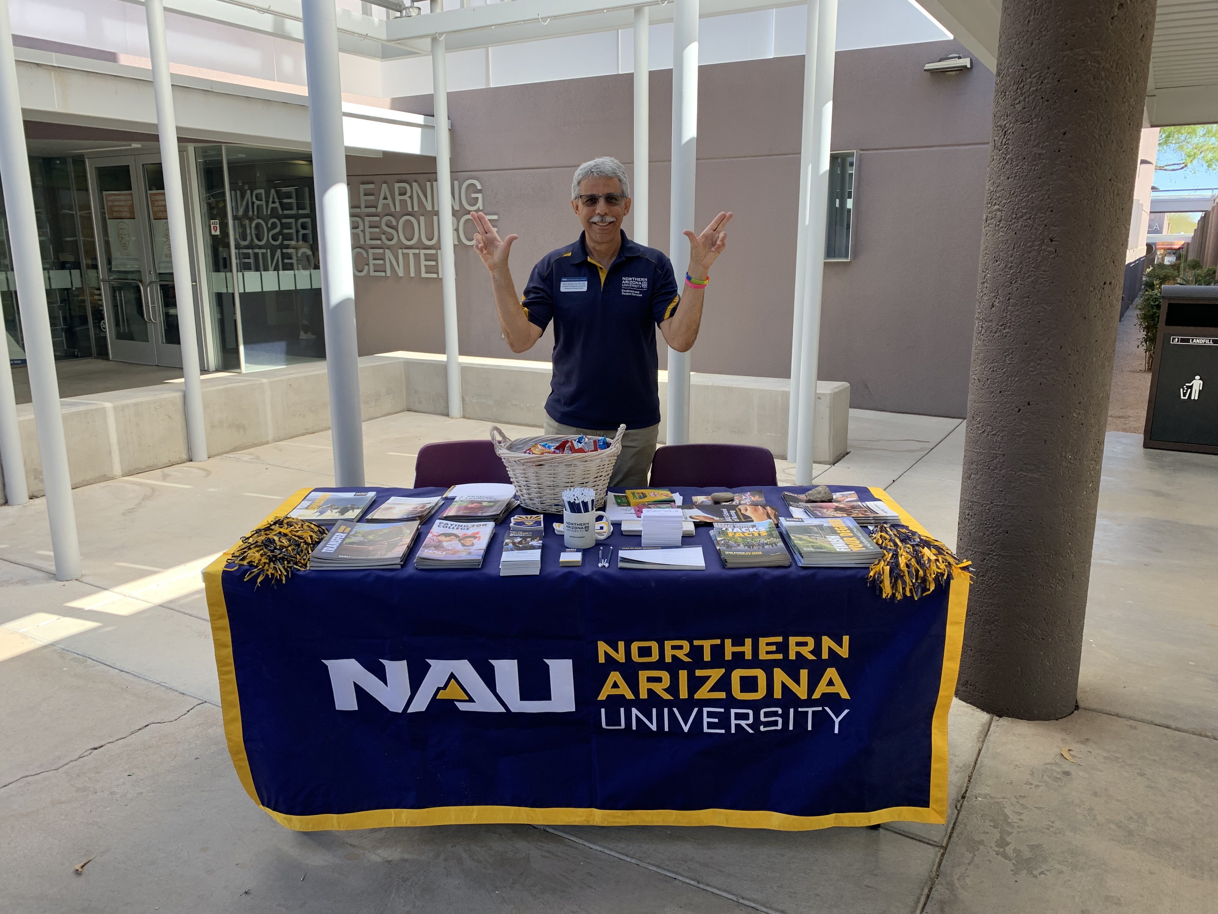 NAU coordinator stands in front of table.