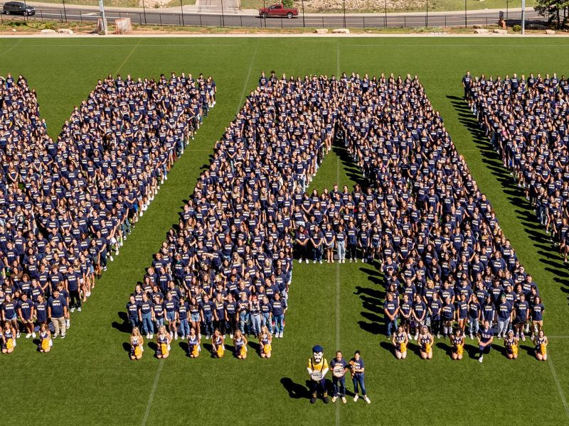 Northern Arizona University graduates spell out N A U on the football field