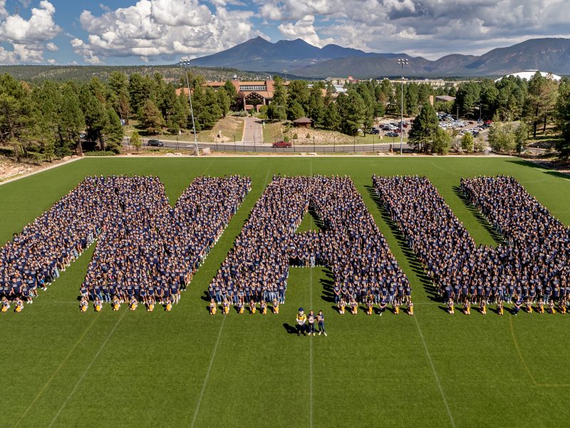 Graduates don Northern Arizona University attire, forming the letters N A U.