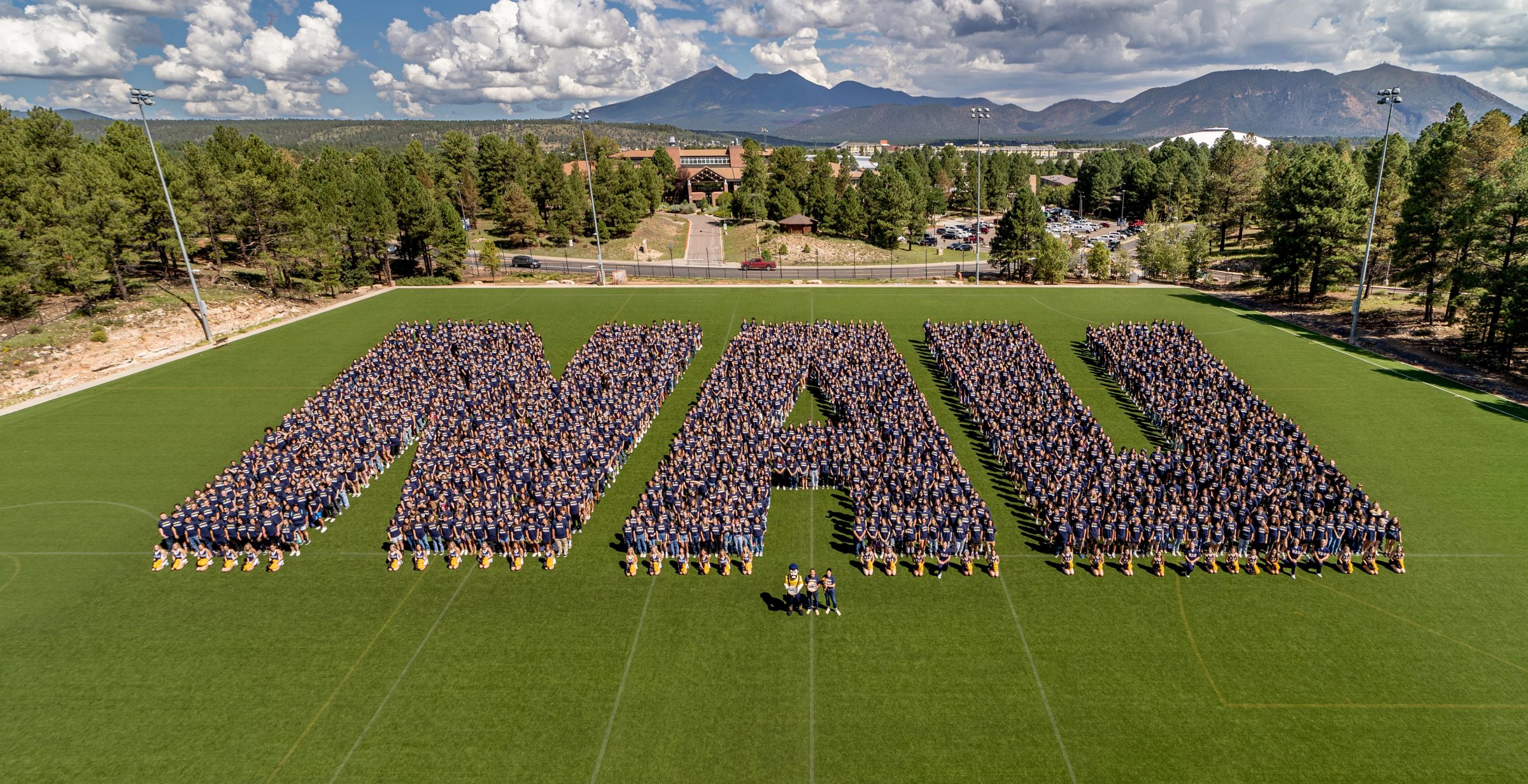 Graduates don Northern Arizona University attire, forming the letters N A U.