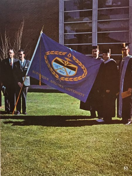 N A U graduates, class of '66, hold a flag with N A U's Academic Crest.
