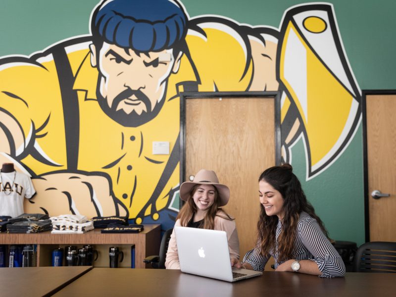 Two students work at the N A U Bookstore.