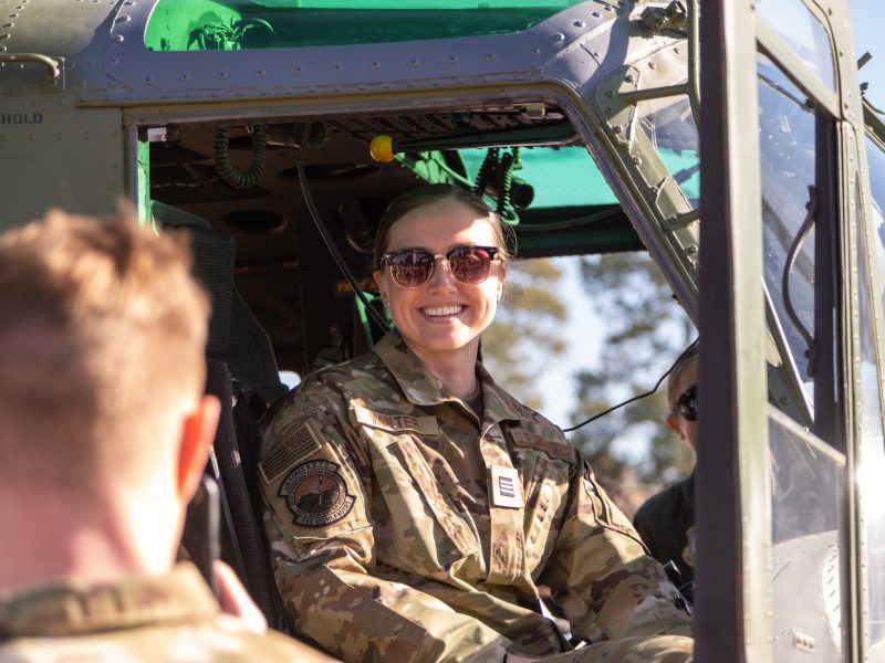 A military officer sits and smiles in a helicopter.