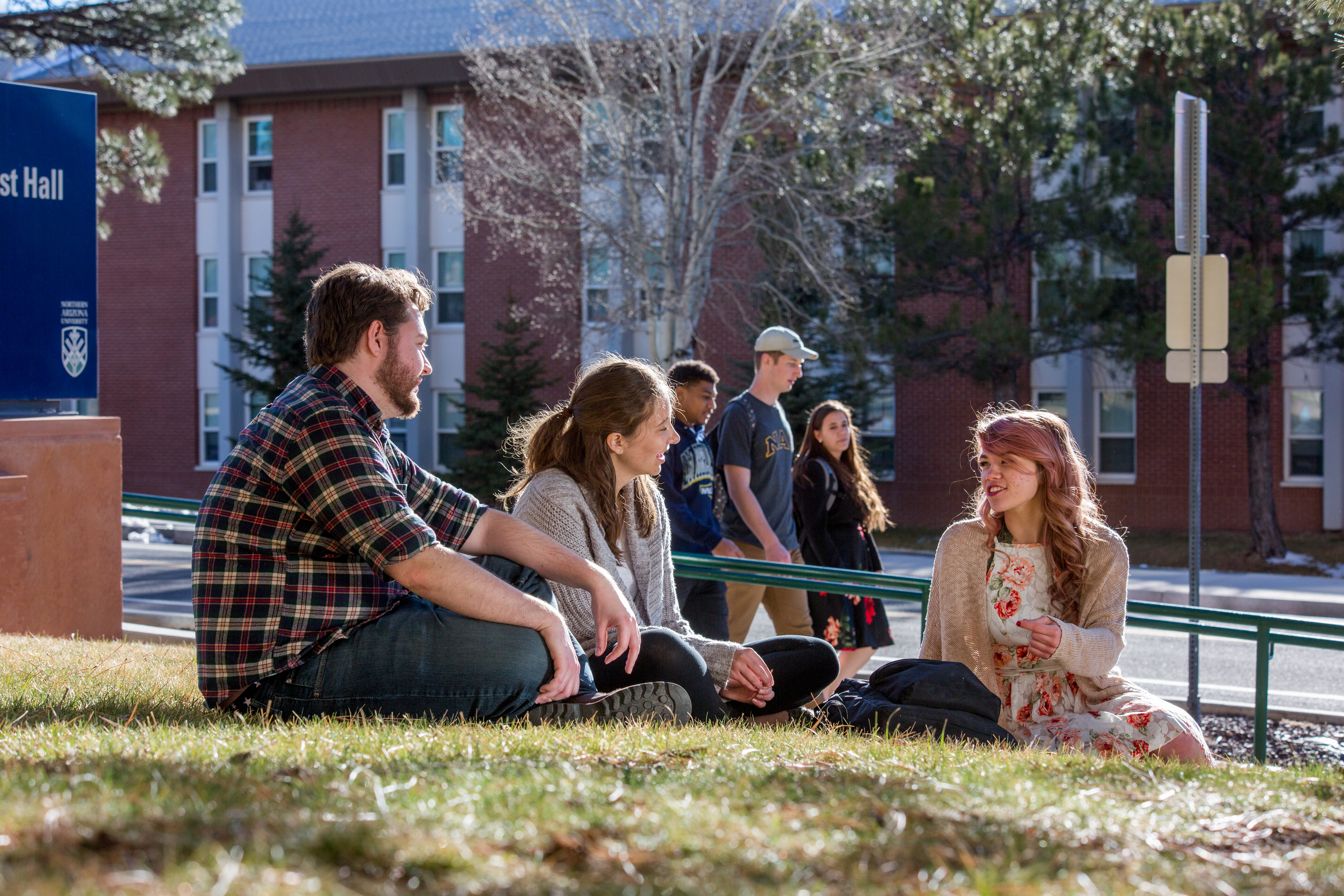 Students talking outside while sitting in the grass.